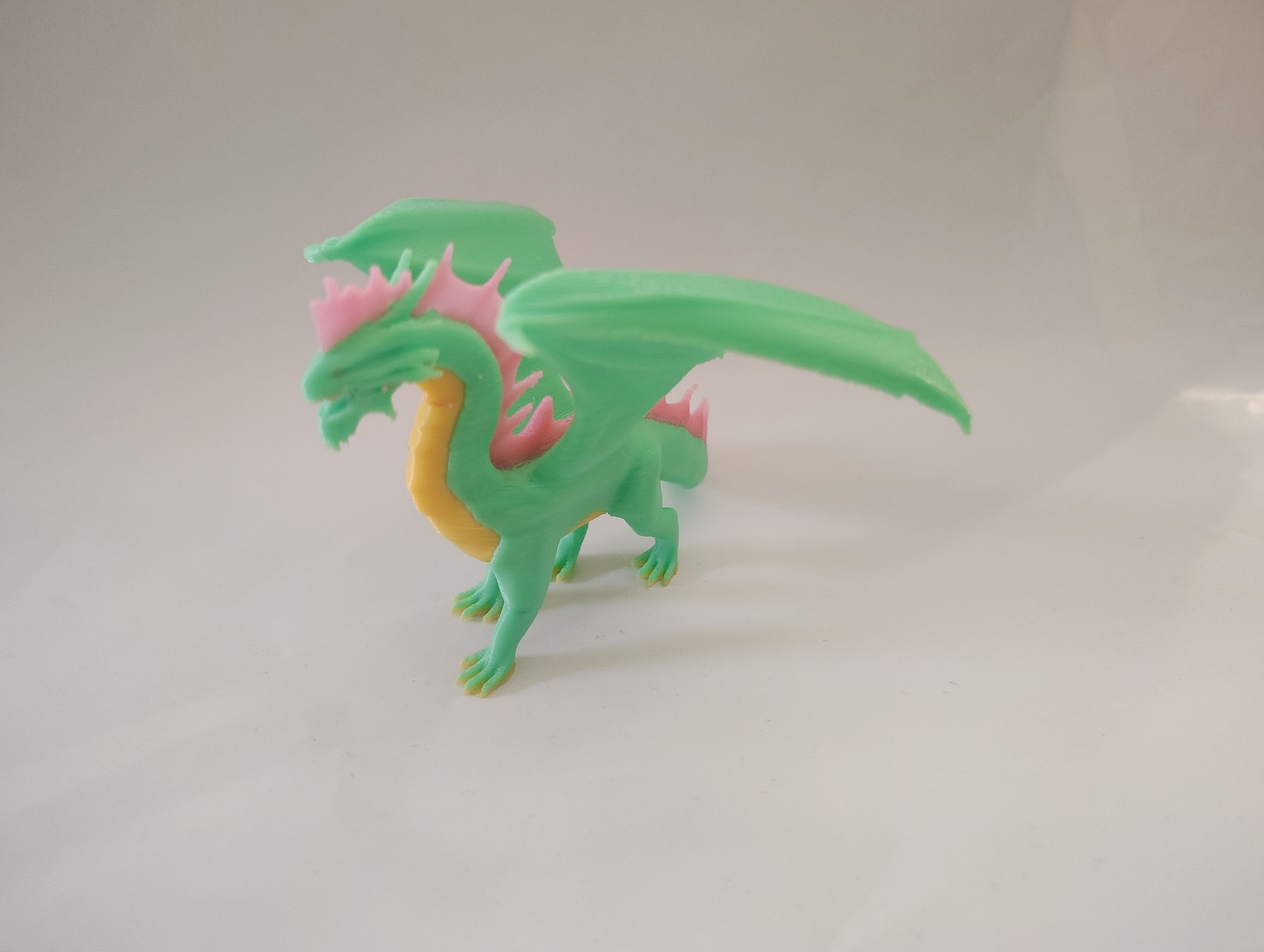 Mint, pink, and yellow 3D-printed dragon figurine
